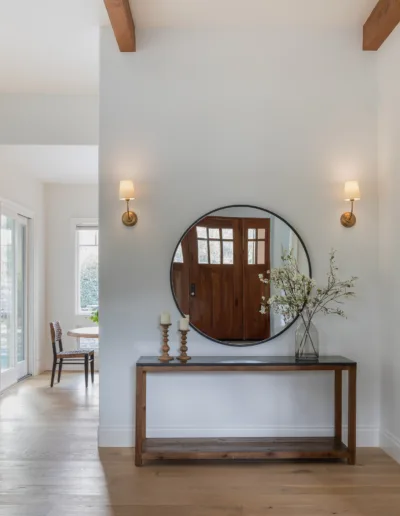 An entryway with hardwood floors and a round mirror.