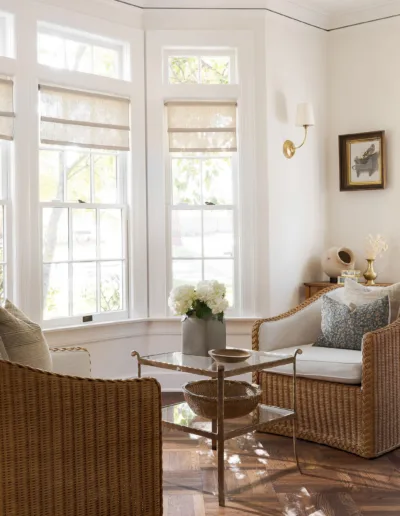 A living room with large windows and wicker chairs.