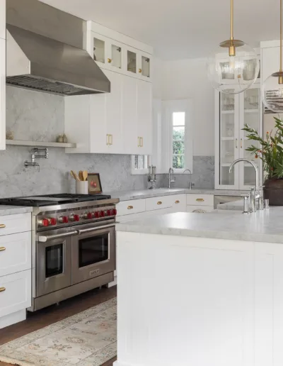 A kitchen with white cabinets and gold accents.