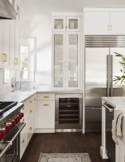 A kitchen with white cabinets and marble counter tops.