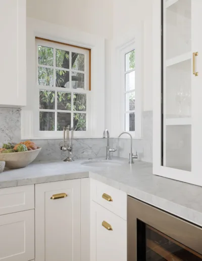 A white kitchen with a window and a wine rack.