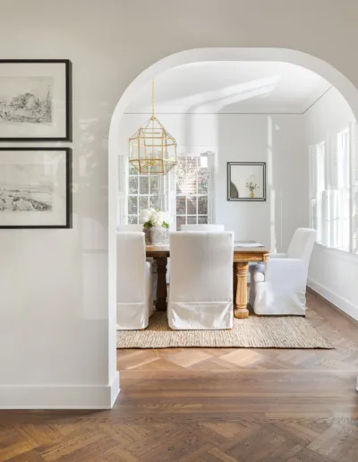 A hallway with an arched door and hardwood floors.