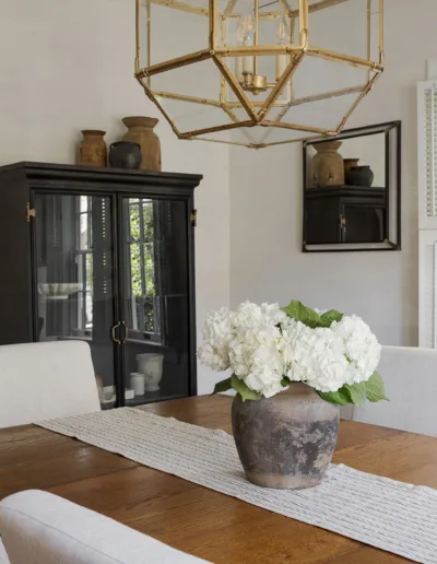 A dining room with white chairs and a chandelier.