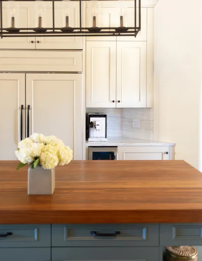 A kitchen with a wooden counter top and white cabinets.